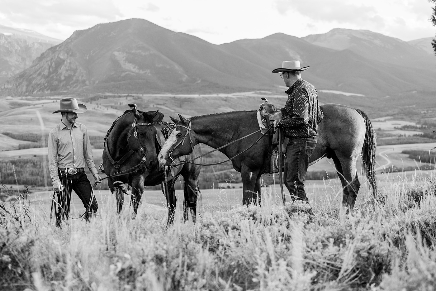 two cowboys next to horses