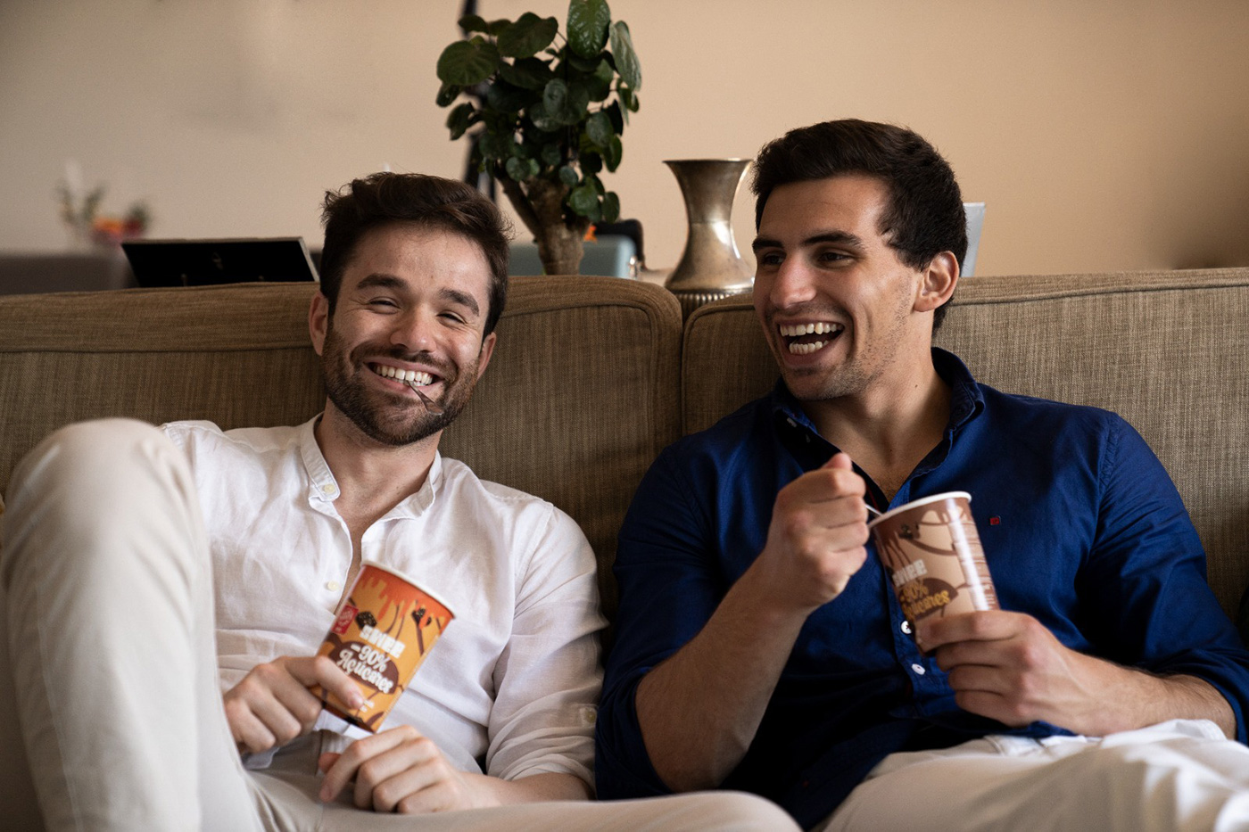 two guys on the couch eating ice cream